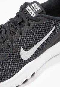 Scarpa da allenamento Nike Flex TR 7 nera con tomaia in mesh, accenti grigi e logo swoosh bianco sul lato. Design leggero con lacci.