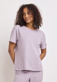 Camiseta de algodón lila con cuello redondo, mangas cortas y un bolsillo en el lado izquierdo. Ajuste holgado y textura suave.