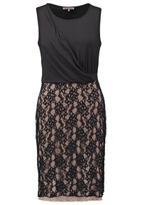 Robe noire sans manches avec haut drapé et jupe nude mi-longue recouverte d'un motif en dentelle florale noire.