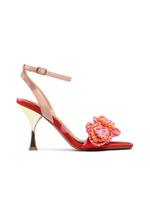 Czerwona sandałka na wysokim obcasie z odkrytymi palcami, z różowym paskiem wokół kostki oraz ozdobnymi różowo-pomarańczowymi szydełkowymi kwiatami z perełkowymi koralikami na przednim pasku.