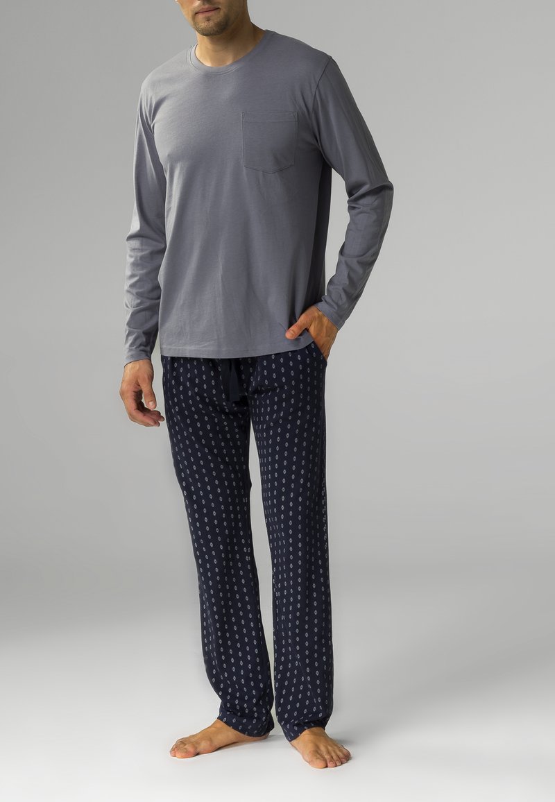 Szara koszula z długim rękawem i kieszonką na piersi, zestawiona z granatowymi spodniami od piżamy w kropeczki, wykonana z miękkiego materiału.