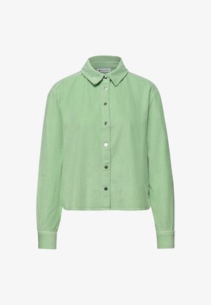 Camisa de pana de manga larga color verde claro con cuello puntiagudo y botones de presión plateados en la parte delantera.