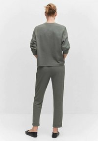 Groene fleecetrui en bijpassende tapered broek met opgerolde boorden, met een relaxte fit en zachte textuur, gecombineerd met zwarte flats.