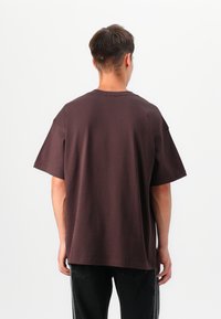 Bordový oversize tričko s krátkymi rukávmi, okrúhlym výstrihom a voľným strihom. Hladký bavlnený materiál, minimálne švy na golieri.