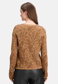Sweatshirt en bronze à motif léopard avec une texture douce, un col large et des manches longues ; associé à un pantalon noir élégant.