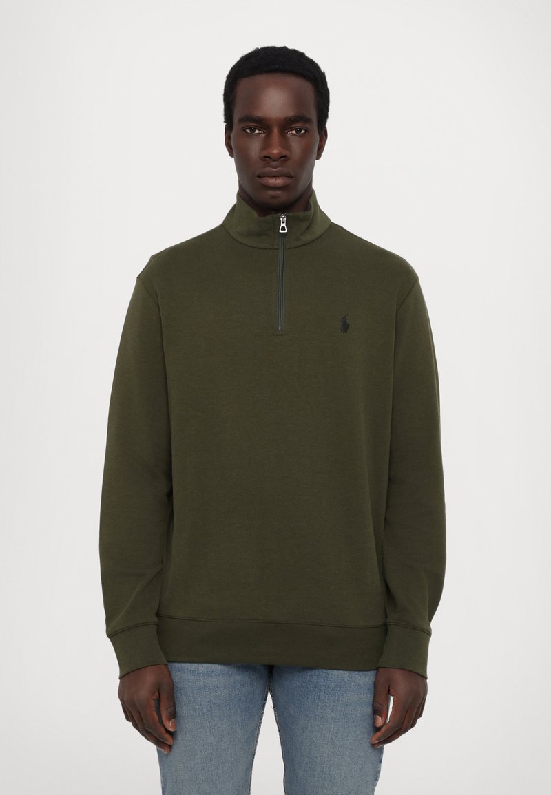 Oliven grøn lynlås sweatshirt med høj krave, lange ærmer, ribbede manchetter og et lille sort logo på venstre bryst.