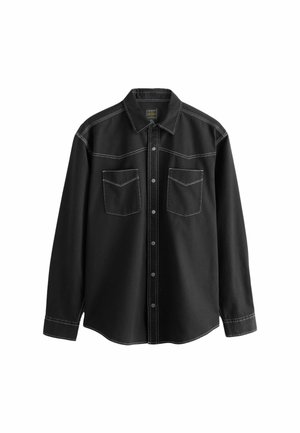 Schwarze Hemdjacke aus Denim-Stoff, mit weißen Nähten, zwei Brusttaschen und einem spitzen Kragen mit langen Ärmeln.