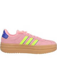 Różowe zamszowe sneakersy z trzema neonowożółtymi paskami, niebieskim akcentem na pięcie oraz grubą brązową gumową podeszwą. Wyposażone w sznurowanie i gładką teksturę.