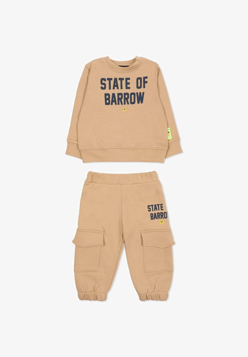 Beżowa polarowa bluza i dopasowane spodnie z napisem "STATE OF BARROW" w ciemnoniebieskim kolorze. Spodnie mają kieszenie cargo i ściągacze przy nogawkach.