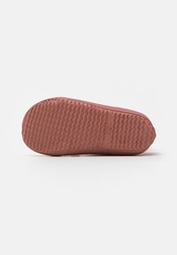 Rubberen schoenzool in terracotta kleur, met een gestructureerd oppervlak met een golvend patroon voor grip en een afgeronde neusvorm.