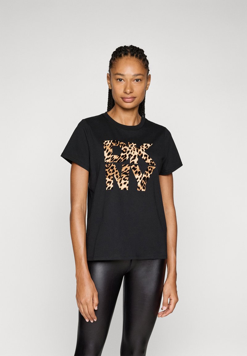T-shirt nera in cotone con logo DKNM a stampa leopardata. La maglietta ha maniche corte e un collo rotondo, abbinata a leggings neri.