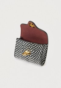 Μικρή τσάντα σε μαύρο και άσπρο με υφή και χρυσό κούμπωμα, ανοιχτό καπάκι που αποκαλύπτει εσωτερικό από σκούρο κόκκινο σουέντ σε ανοιχτό φόντο.