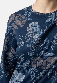Maglietta a maniche lunghe di colore blu navy con un motivo floreale in azzurro chiaro e beige. Collo rotondo e texture morbida con dettagli lineari intricati sui fiori.