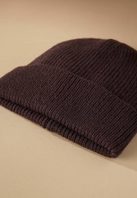 Knit beanie in dark brown, featuring a ribbed texture and fold-over cuff. Made from soft material, ensuring warmth and comfort.