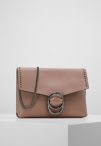 Rosa läderhandväska med en vikbar klaff, kedjestropp, silverfärgade detaljer, nubbdetaljer längs kanten och en cirkulär accent på framsidan.