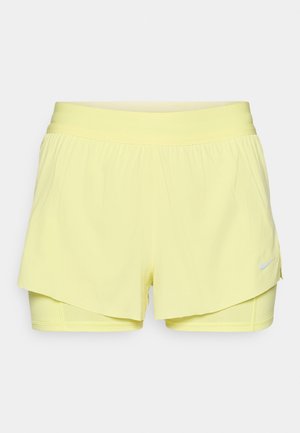 Shorts de sport jaune avec une taille élastique, un design superposé et un logo Nike blanc sur le coin inférieur droit.