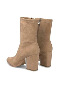 Par de botas de ante color canela hasta la mitad de la pantorrilla, con tacones de bloque y cremalleras laterales, mostradas desde atrás y ligeramente anguladas hacia un lado.