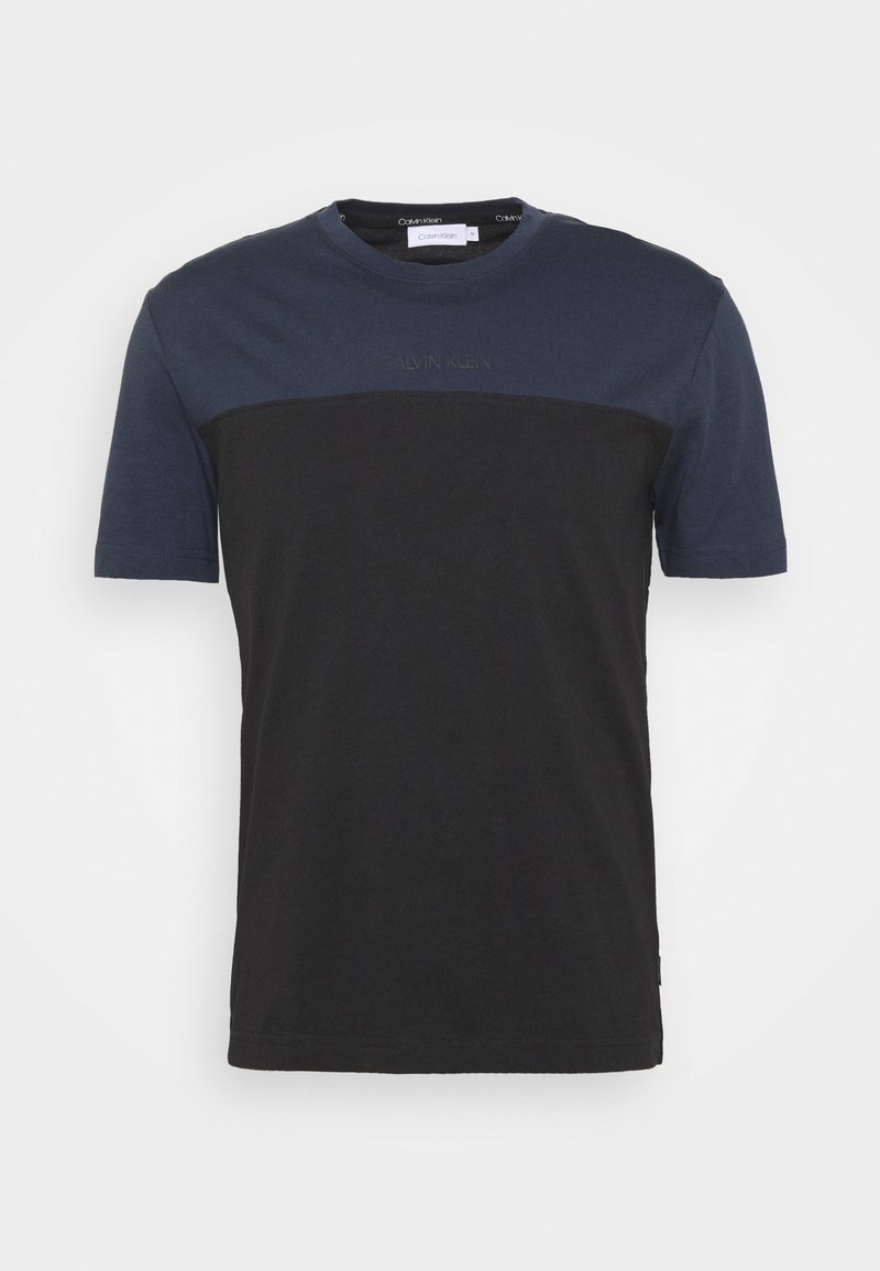 Camiseta de manga corta con la parte superior en azul marino y la sección inferior en negro. Hecha de algodón, presenta un cuello redondo y un logo sutil en el pecho.