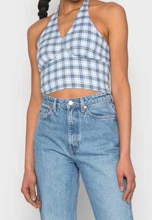 Woman wearing a blue and white plaid halter crop top paired with high-waisted light blue denim jeans.