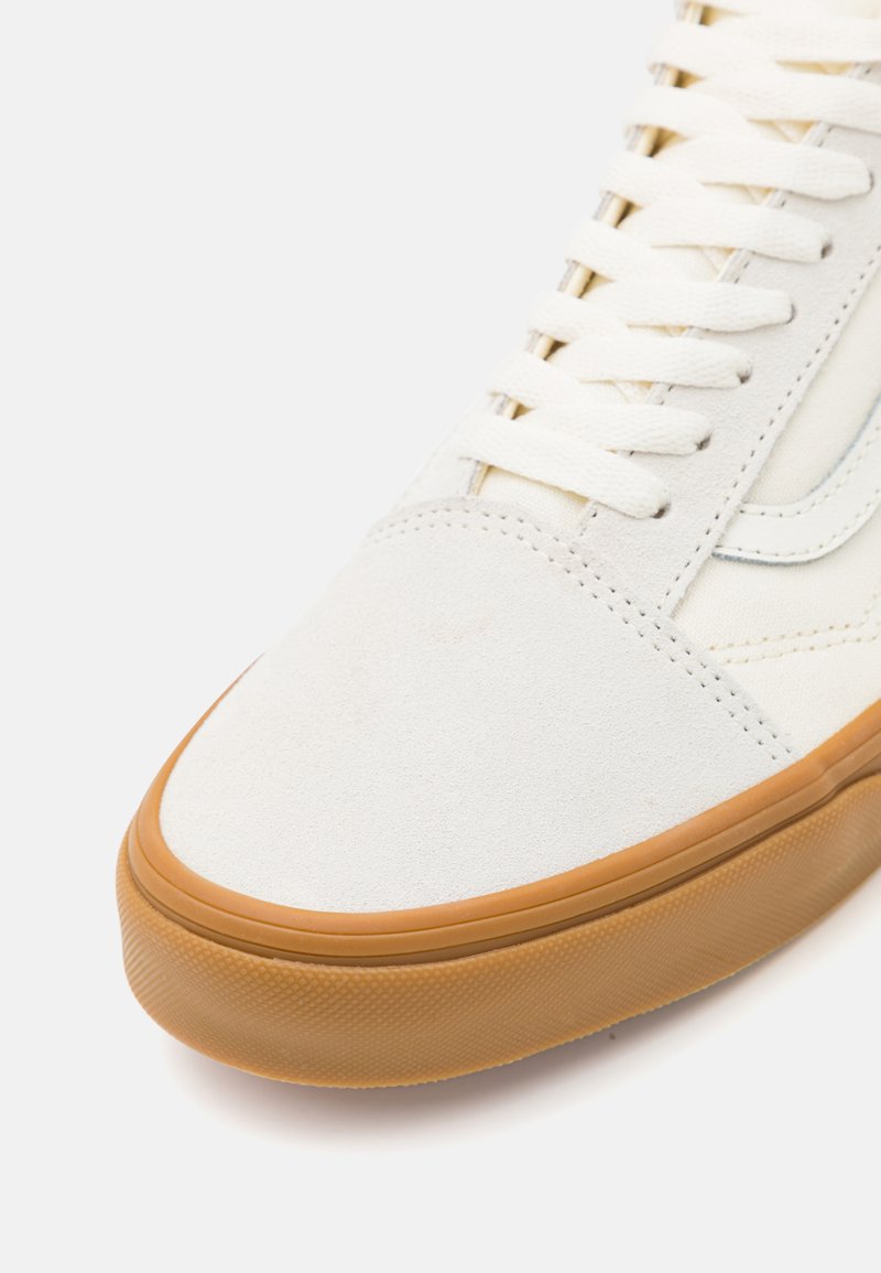 Zapatillas de suede blancas con suela de goma, cordones planos y un diseño minimalista con detalles de costura sutiles.