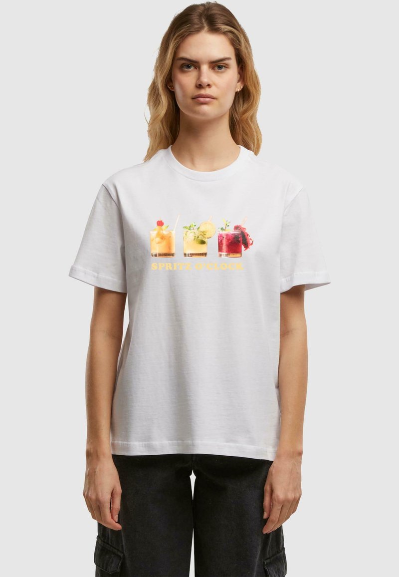 Camiseta de algodón blanca con un gráfico de cuatro cócteles coloridos y el texto "SPRITZ O'CLOCK" en amarillo, con cuello redondo y mangas cortas.