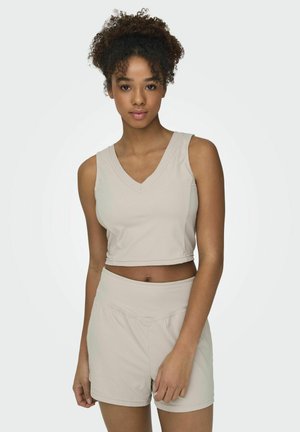 Lyse beige ribbet crop top med V-hals og matchende højtaljede shorts, der fremhæver en blød tekstur og en tætsiddende design.