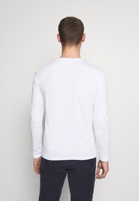 Weißes Langarm-T-Shirt mit Rundhalsausschnitt, aus glattem Baumwollstoff gefertigt. Schlichtes Design, keine sichtbaren Muster oder Akzente.