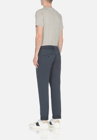 Pantaloni blu navy realizzati in un materiale leggero, con una vestibilità su misura, tasche posteriori e risvolti, abbinati a una maglietta grigia e sneakers bianche.