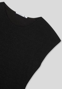 Camicia nera con una trama liscia, maniche ampie a taglio angolato e scollo arrotondato. Tessuto con un leggero luccichio. Etichetta della taglia visibile.