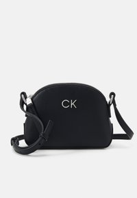Borsa a tracolla nera in pelle con logo argentato, forma arrotondata, chiusura con zip e tracolla regolabile. Superficie testurizzata con accenti minimi.