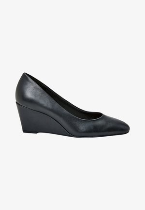 Zapato de tacón cuña negro hecho de cuero, con puntera redondeada y textura suave. La cuña es triangular y eleva desde la parte trasera hacia la delantera.
