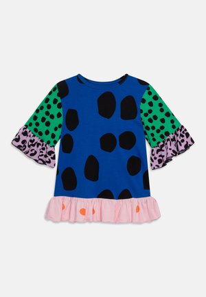 Top azul de manga corta con manchas negras, mangas con patrones verdes y morados, y dobladillo con volantes rosa con puntos naranjas.