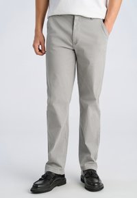 Graue Baumwoll-Chinos mit Gürtelschlaufen und Seitentaschen, gerade geschnitten, kombiniert mit schwarzen Loafers mit Fransenakzenten.