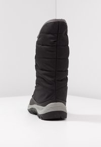 Botte noire isolée avec une tige matelassée et rembourrée, et une semelle en caoutchouc grise. L'arrière présente une texture lisse et une silhouette haute.