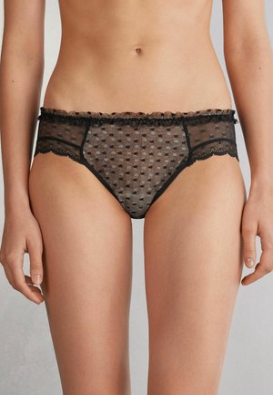Zwarte netpanty met stippenpatroon, met een gerimpelde tailleband en kantafwerking langs de randen voor extra detail.