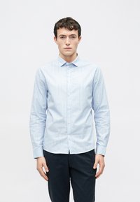 Jasnoniebieska koszula w paski na guziki, z kołnierzykiem, długimi rękawami i prostym dołem. Tkanina wydaje się gładka i lekko połyskująca.
