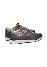 Zapatos de cuero marrón con acentos de textil gris, que presentan cordones rojos y una suela blanca. Punta redondeada y detalles perforados en los laterales.
