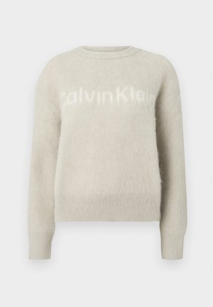 Svetlo šedý sveter z mäkkej textúrovanej látky s voľným strihom a okrúhlym výstrihom. Na prednej strane je zobrazené meno značky 'CalvinKlein' v bielej farbe.