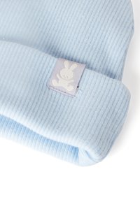 Světlomodrá žebrovaná čepice s přehnutým okrajem. Má štítek s bílou siluetou králíka. Měkká, strukturovaná tkanina, navržená pro pohodlí.