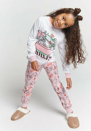 White long-sleeve pajama top with pink accents and cartoon graphic. Pink pajamas with a repeating Hello Kitty pattern. Tan slippers with white lining.