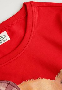 Czerwona bawełniana koszulka z okrągłym dekoltem, krótkimi rękawami i nadrukiem postaci z kreskówki z przodu. Miękka tekstura, casualowy styl.