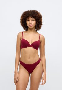 Μαροόν σουτιέν και αντίστοιχο μπικίνι, με απαλό ύφασμα, ρυθμιζόμενους ιμάντες και κλασικό σχέδιο με ελάχιστες λεπτομέρειες.