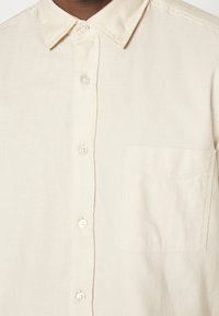 Lichtbeige knoopsluiting shirt van katoen, met een klassieke kraag, een borstzak en een subtiele textuur met afgeronde knopen.