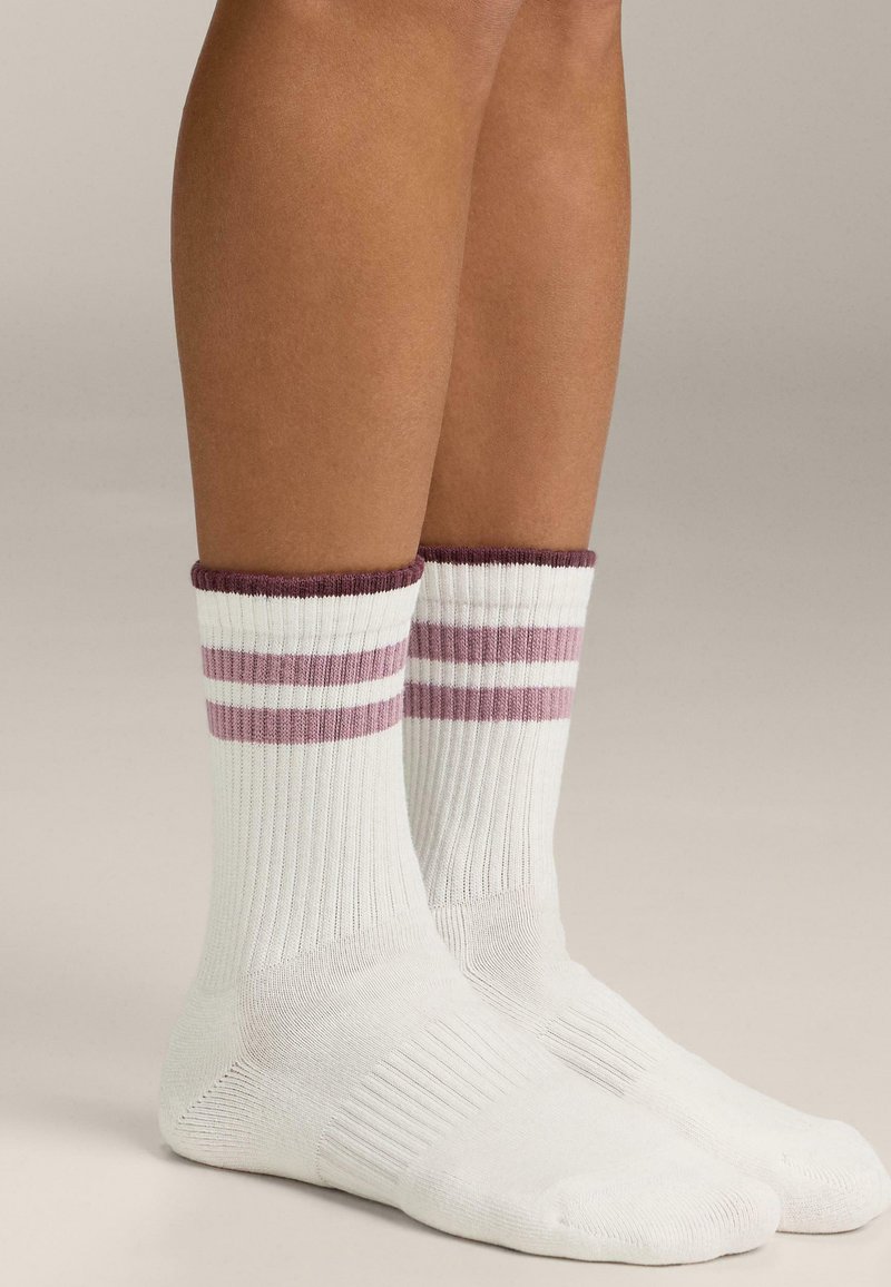 Fehér pamutzokni bordázott mintával, bordó mandzsettával és a boka felett két vízszintes rózsaszín csíkkal.