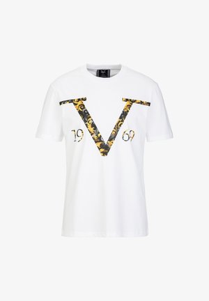 Witte katoenen t-shirt met een groot zwart en gouden patroon van een "V" en "1969" gedrukt op de voorkant. Korte mouwen, ronde hals.