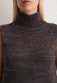 Donkergrijze, mouwloze gebreide coltrui met ribbeltextuur en details, met een hoge kraag en een dik garenpatroon.