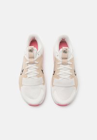 Zapatillas deportivas blancas y beige con parte superior de malla texturizada, cordones planos y detalles rosas en el talón, con una correa sobre la lengüeta.