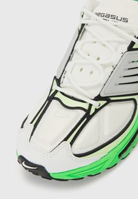 Nike Pegasus tenisice s gornjim dijelom od bijele mrežice, zelenim naglascima, crnim detaljima i zaštitnom sivom oblogom s teksturiranom završnom obradom.