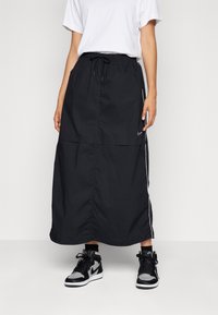 Svart, lättvikts, ankellång kjol med elastisk midja, snörning, sidostråkar och rynkdetalj längst ner.