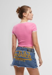 Roosa ribatud lühike t-särk valgete äärtega, koos hõrendatud teksaseelikuga, mille tagaküljel on kuldne tikand "Von Dutch" logo.